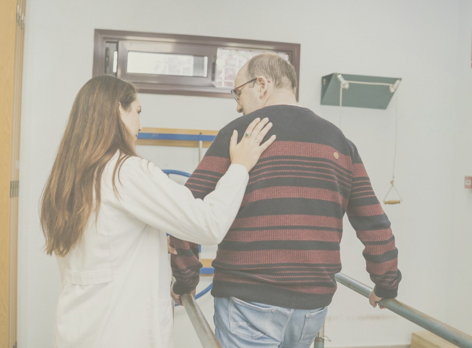 Sesión de rehabilitación en gimnasio con barras paralelas